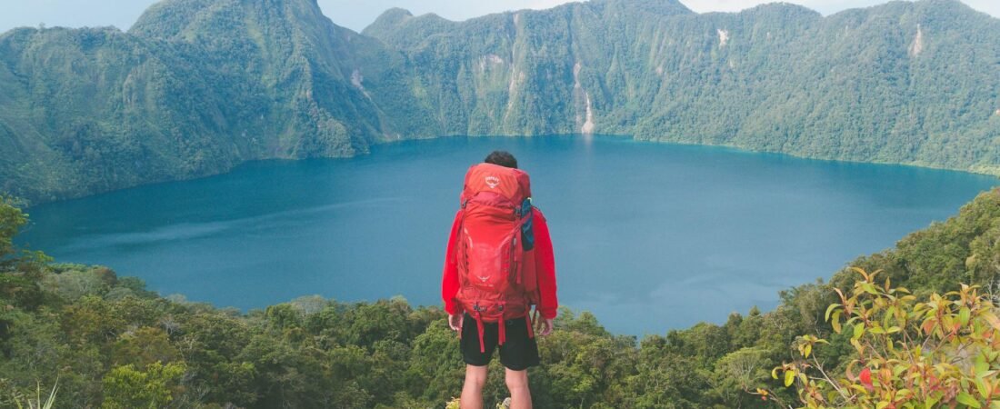 photo of hiker on top of rock facing a lake